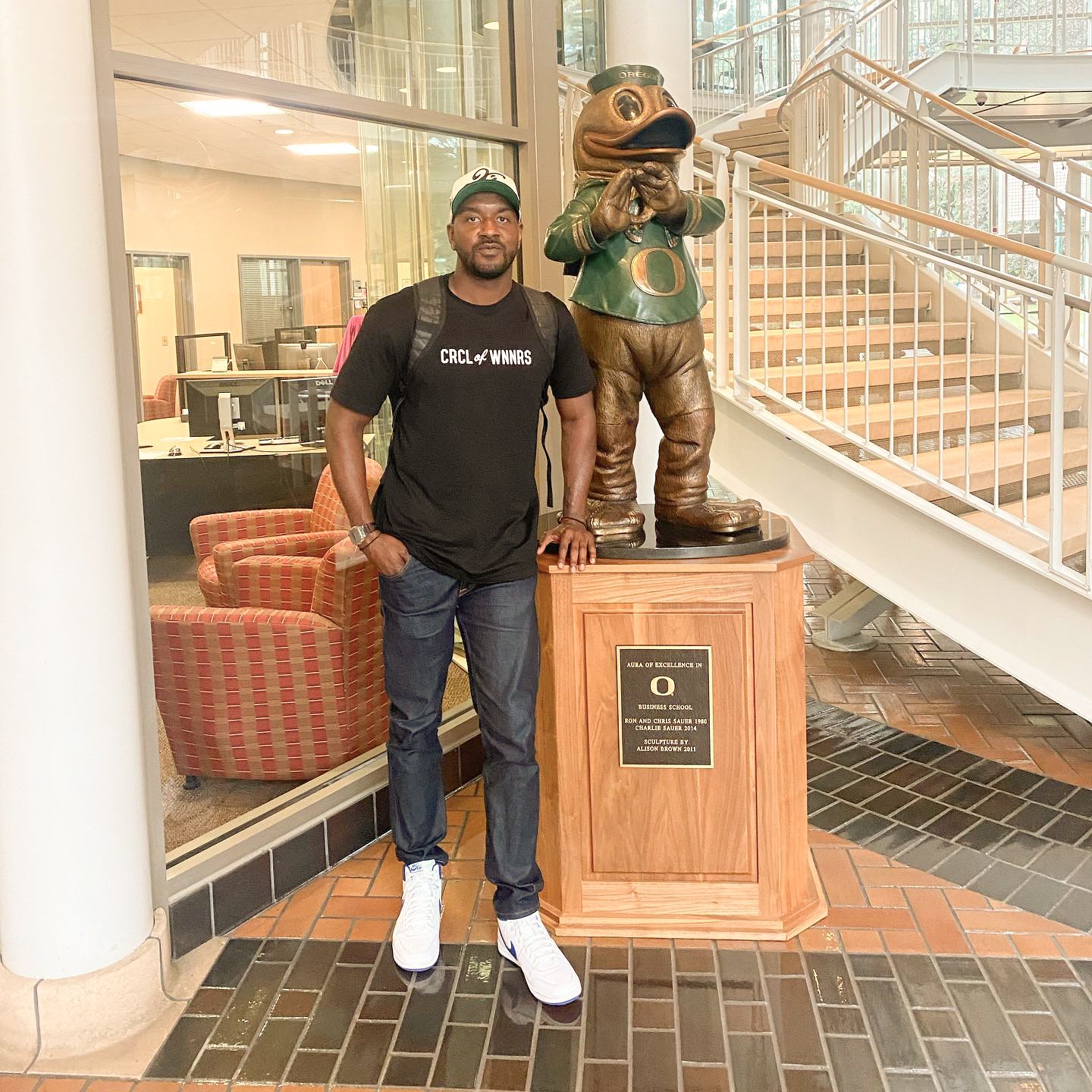 Garren Strong standing next to a bronze statue of the University of Oregon Duck mascott.
