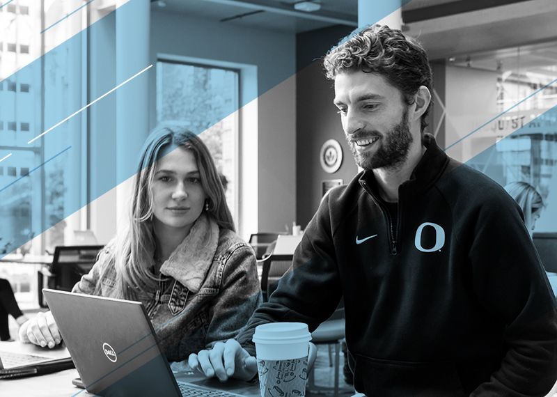 Jeff Sorensen and a student sitting at a table, looking at a laptop.